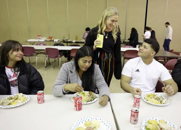 Hope Vaughn, second from right, talks with Manuel Goitia during a potluck Thanksgiving dinner at St. Agatha Catholic Church in Chicago on Nov. 21, 2023. Vaughn was one of the organizers who made traditional Thanksgiving dinner foods to share with migrants.